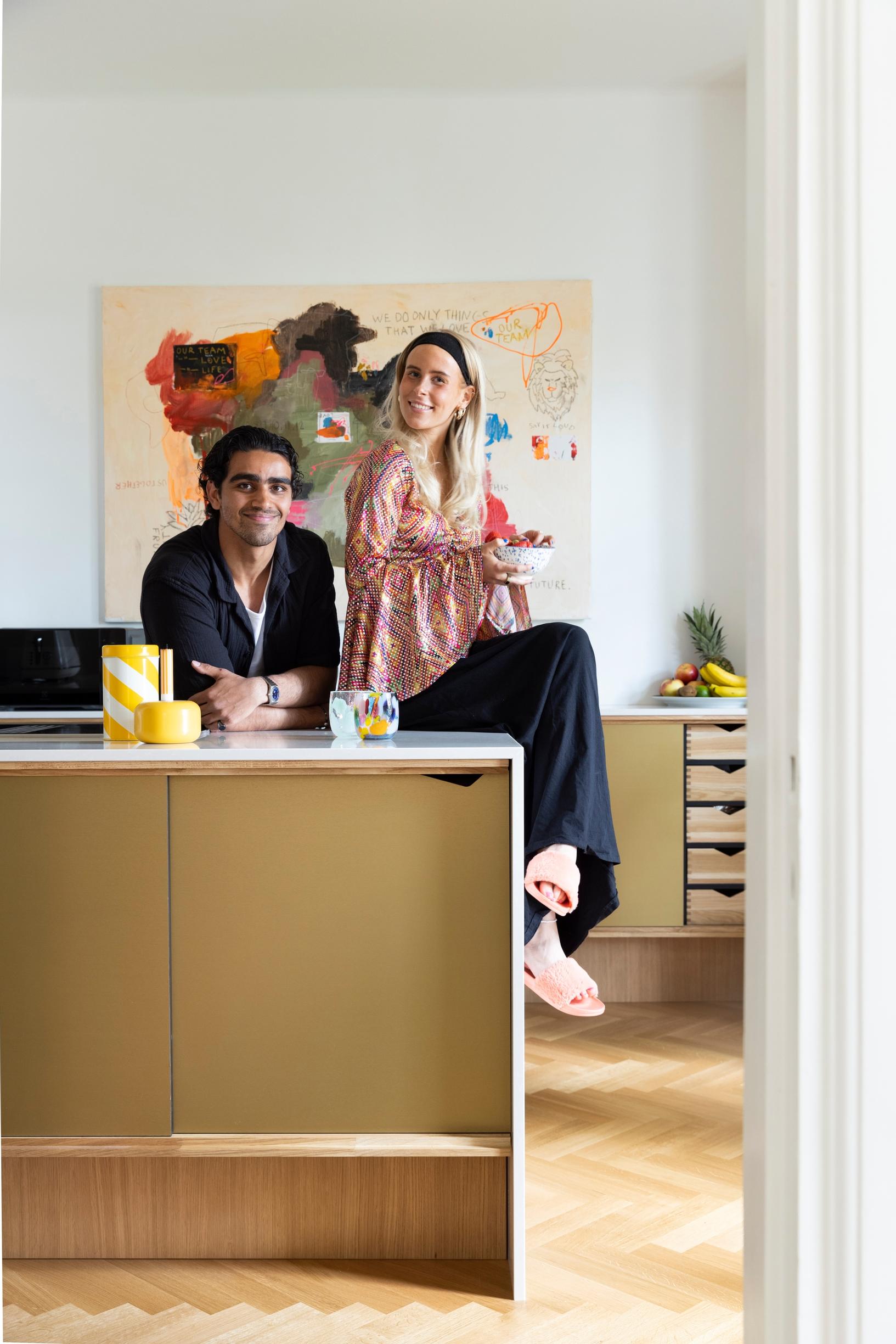 Iiris and Salah in their colorful kitchen, with Iiris’s painting in the background