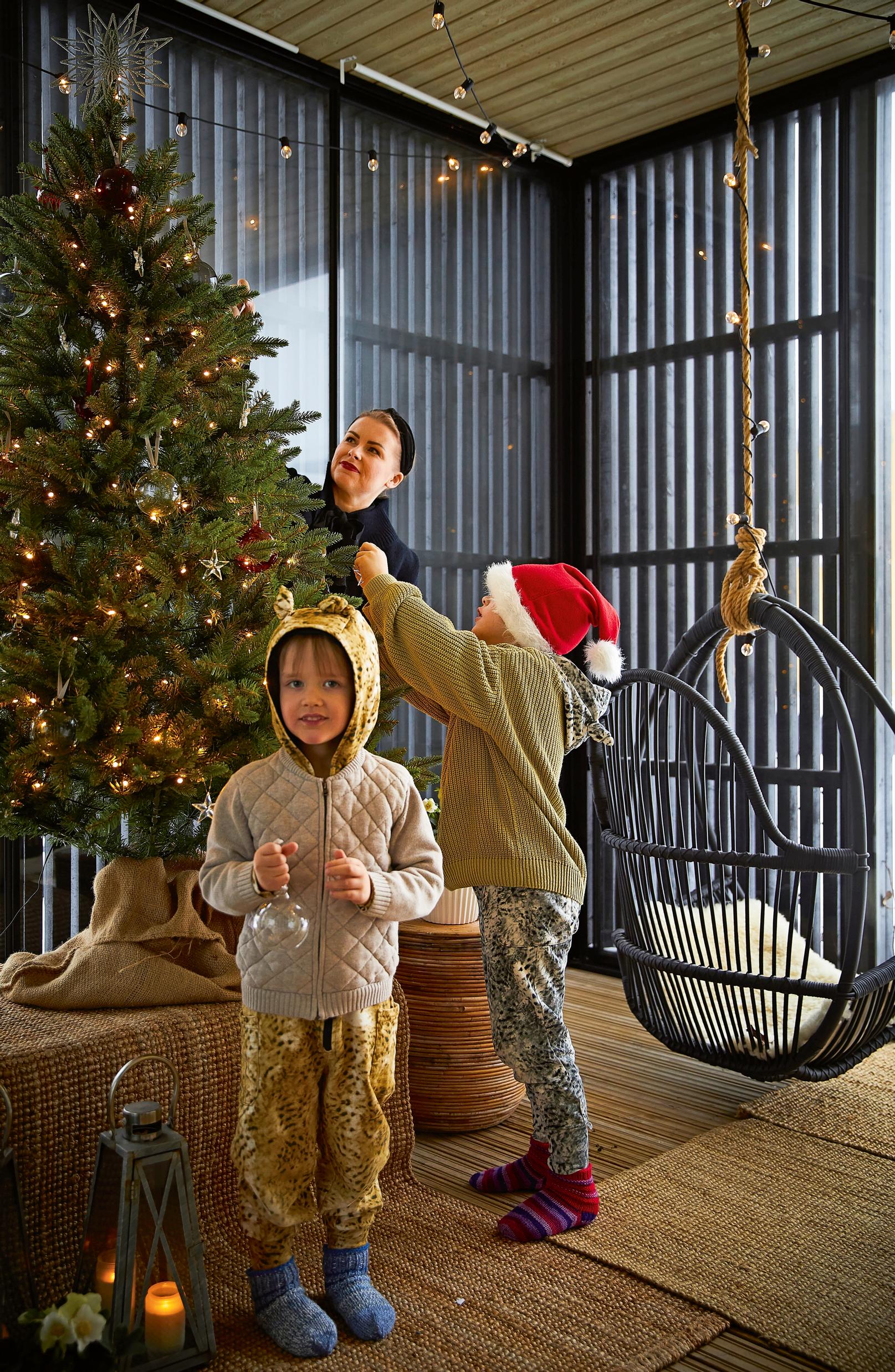 family members decorating the terrace Christmas tree and a hanging chair