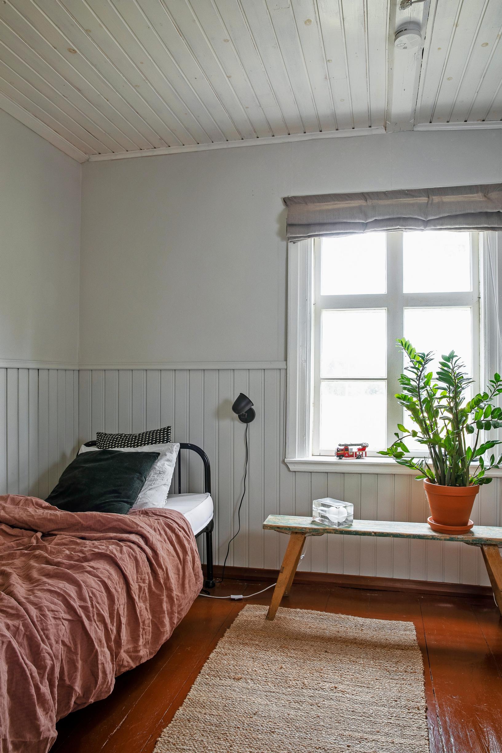 Guest room: Wooden floor painted in red ocher and a guest bed in the same color
