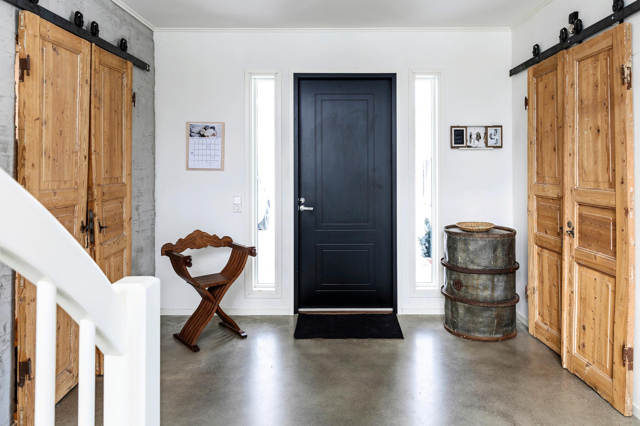 On both sides of the entrance hall, there are sliding double doors made from old doors. At the end wall is a black front door.