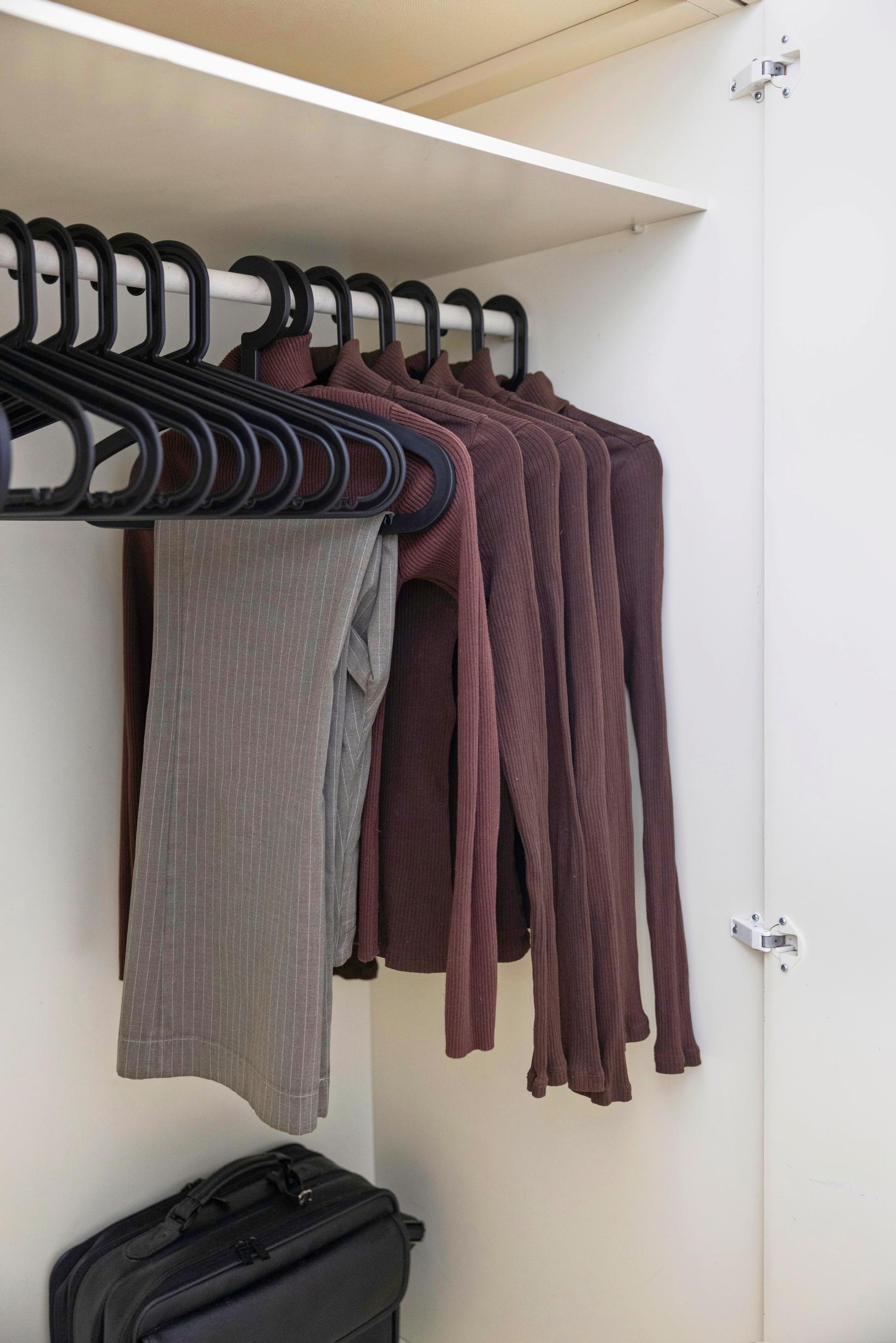 a wardrobe with a row of brown turtleneck shirts and a pair of trousers