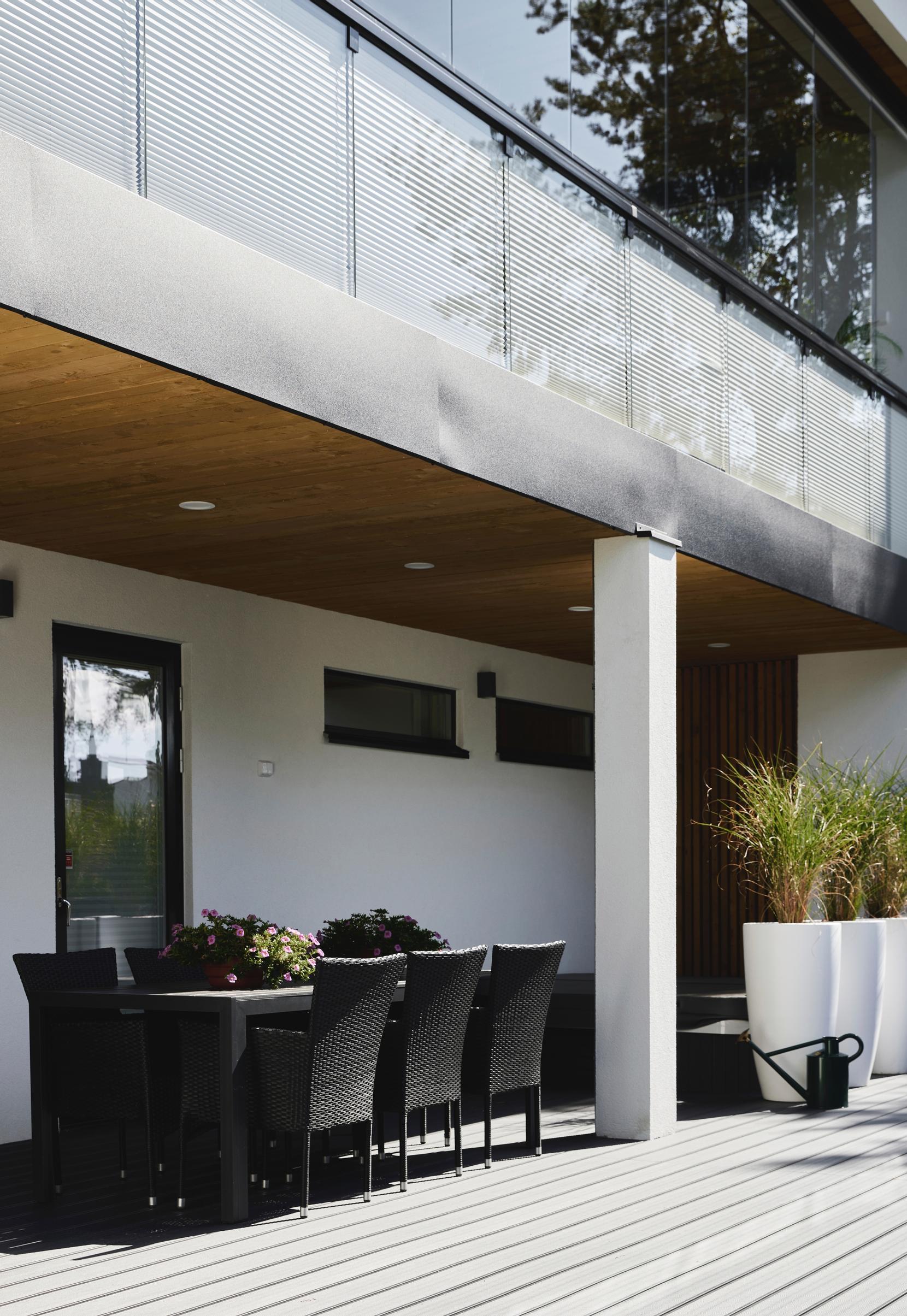 A single-family home’s terrace with an outdoor furniture set and white planters.