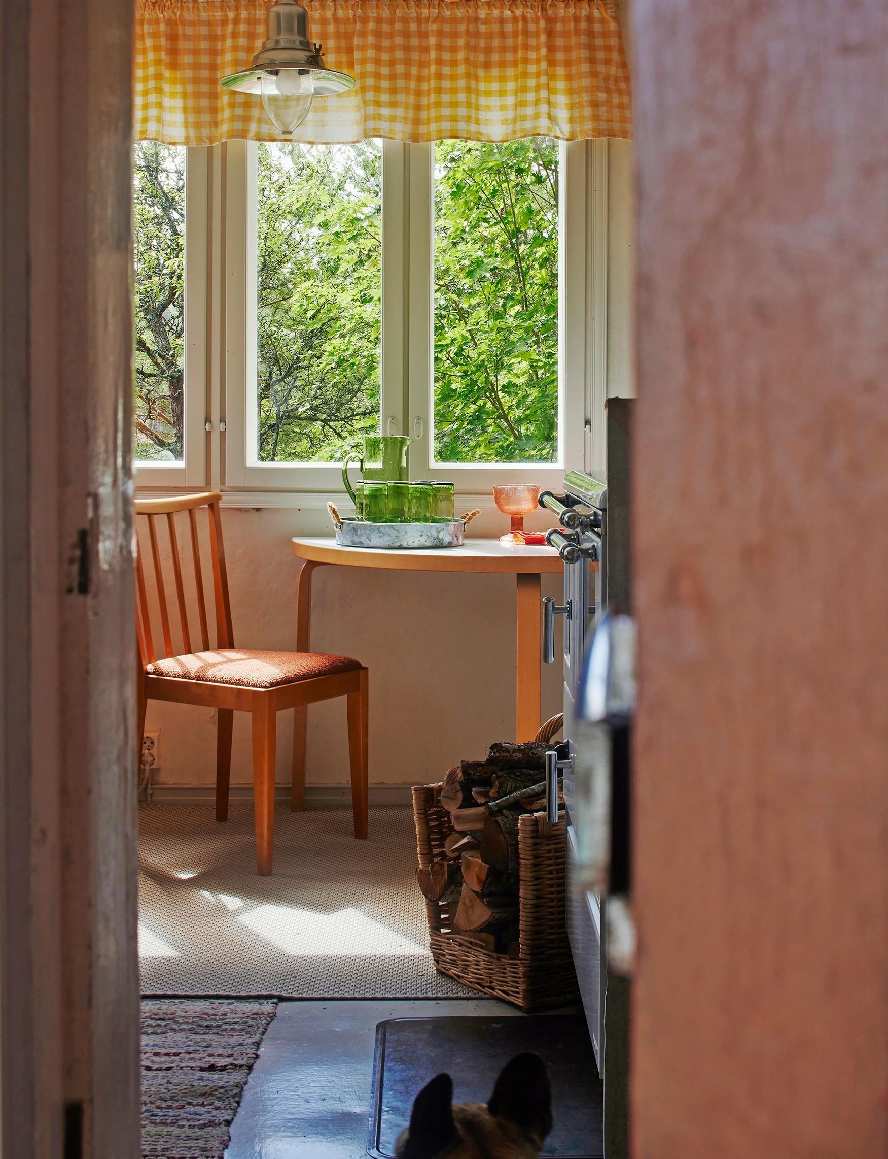 table and chair in front of a window, firewood in a carrying frame