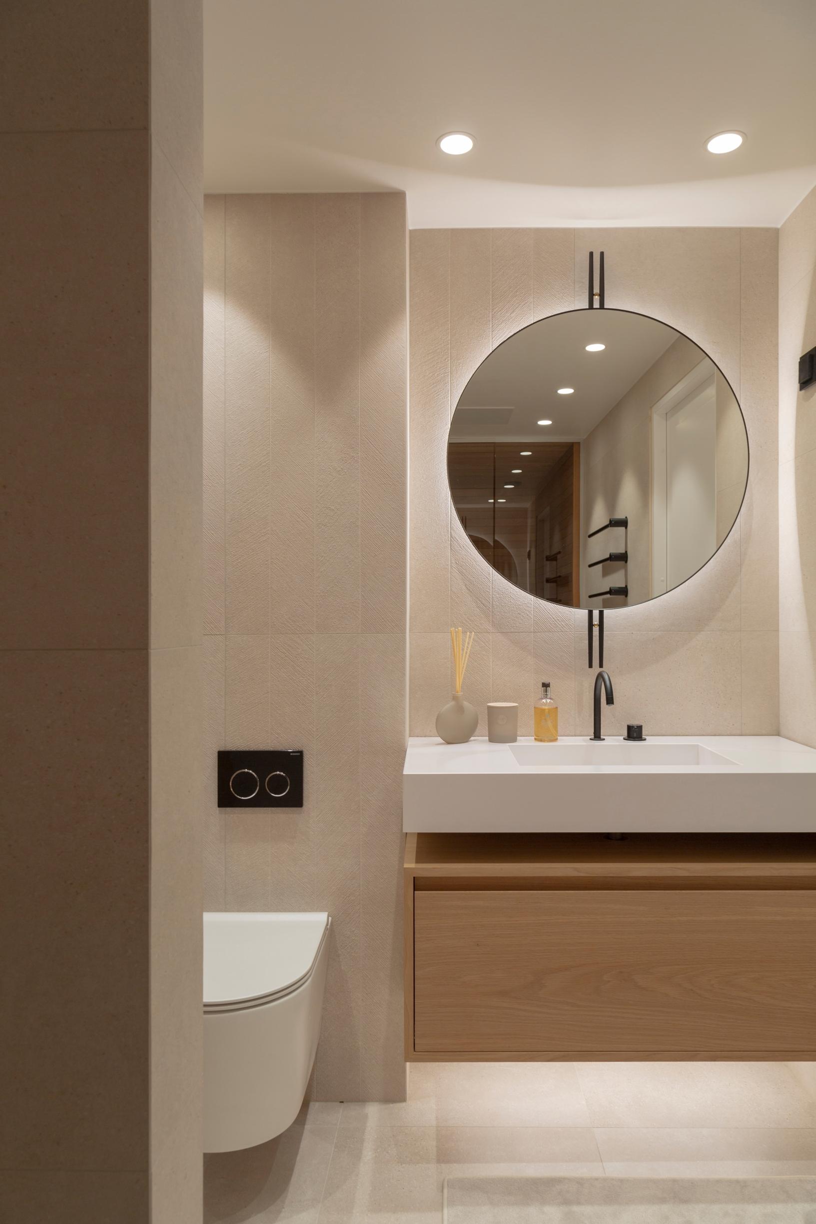 An apartment bathroom divided into three zones, featuring a solid oak vanity