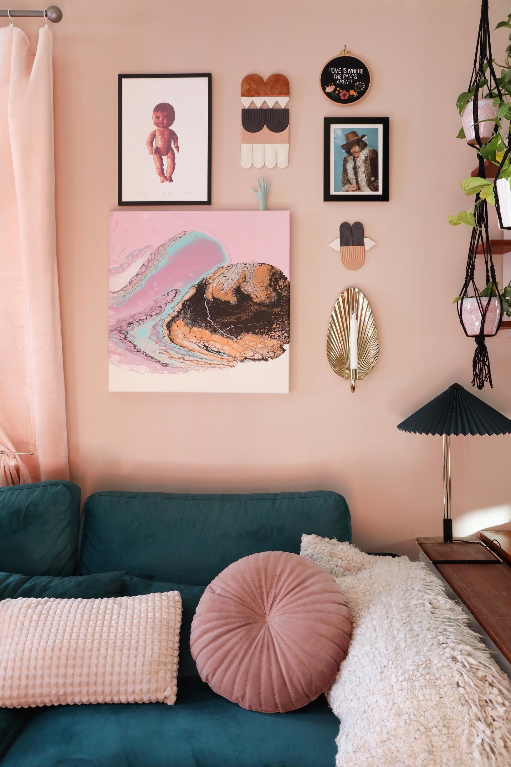 A collage of paintings and objects on a pink wall