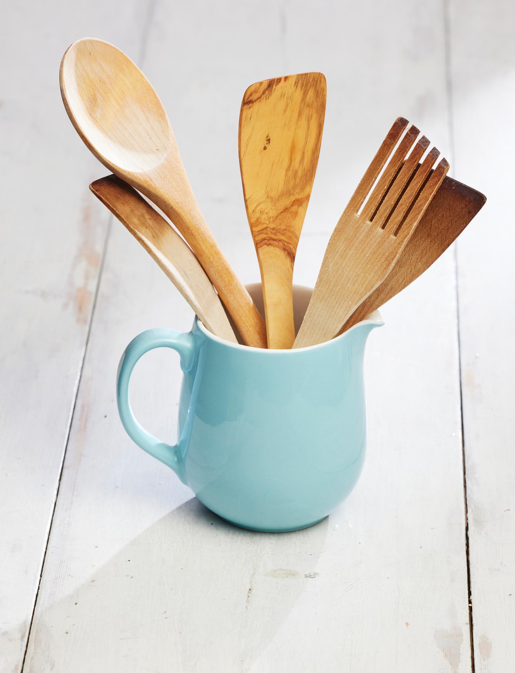An old Arabia milk pitcher holding wooden ladles.