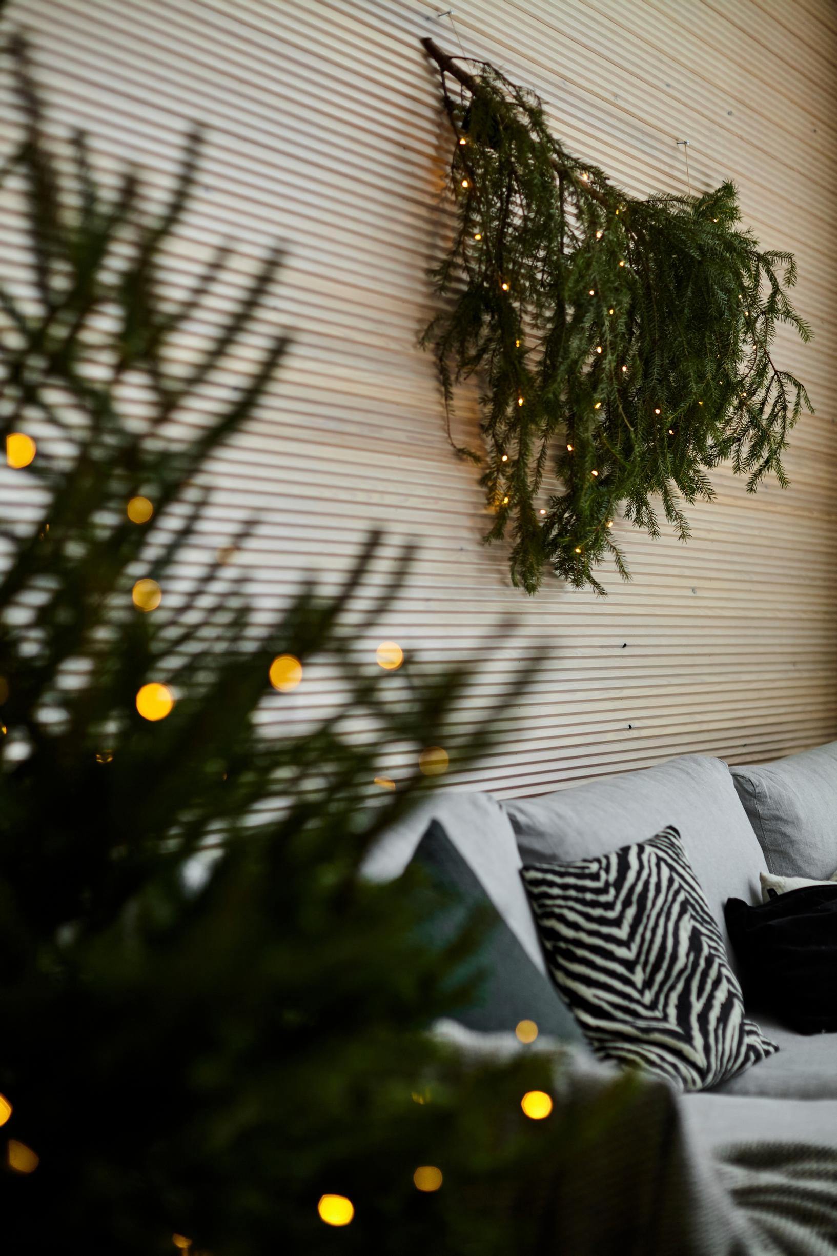 a Christmas tree next to the sofa and a conifer decoration above it