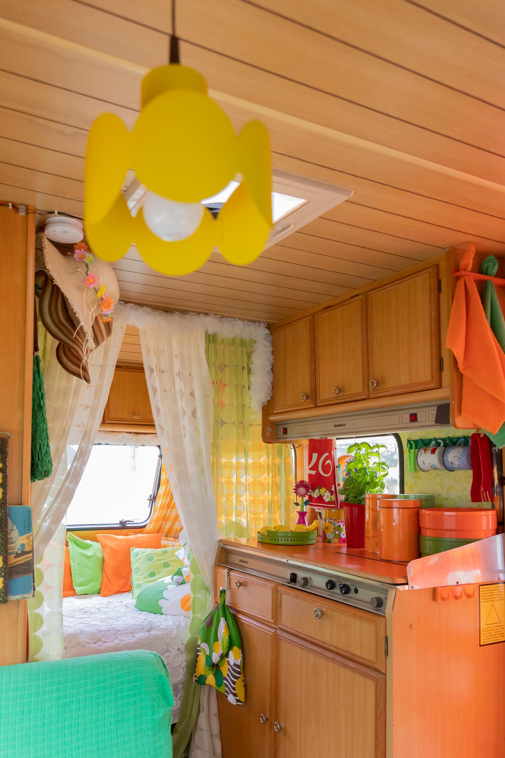 a yellow retro lamp on the ceiling, kitchen cabinets, and a sofa nook in the travel trailer