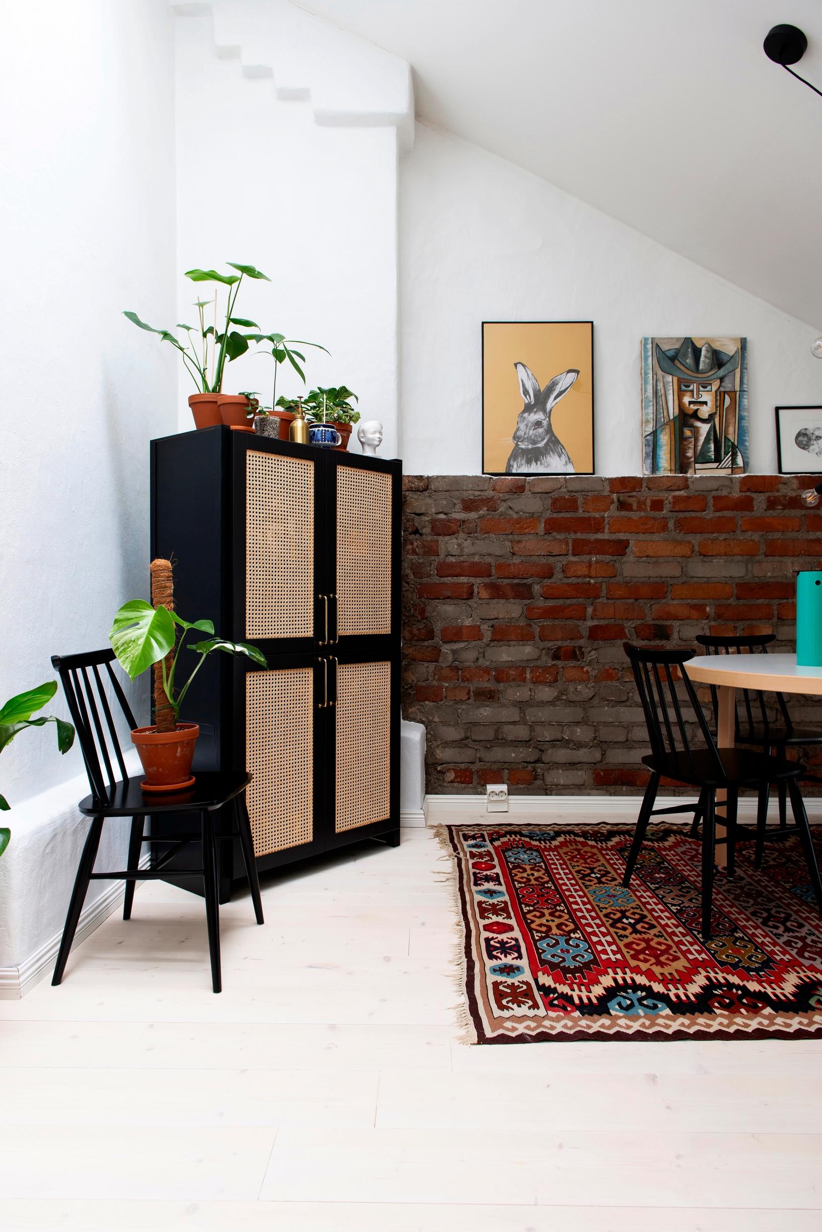 Photo of a cabinet with rattan doors and a brick wall.