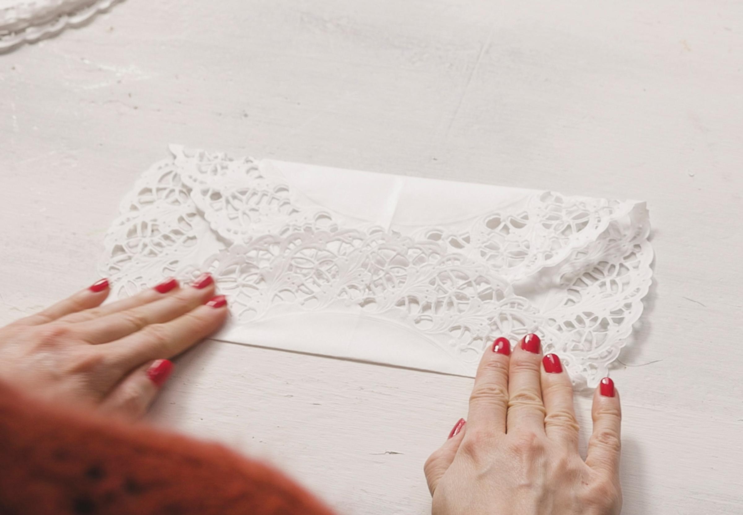 Folding the top and bottom edges of the paper doily