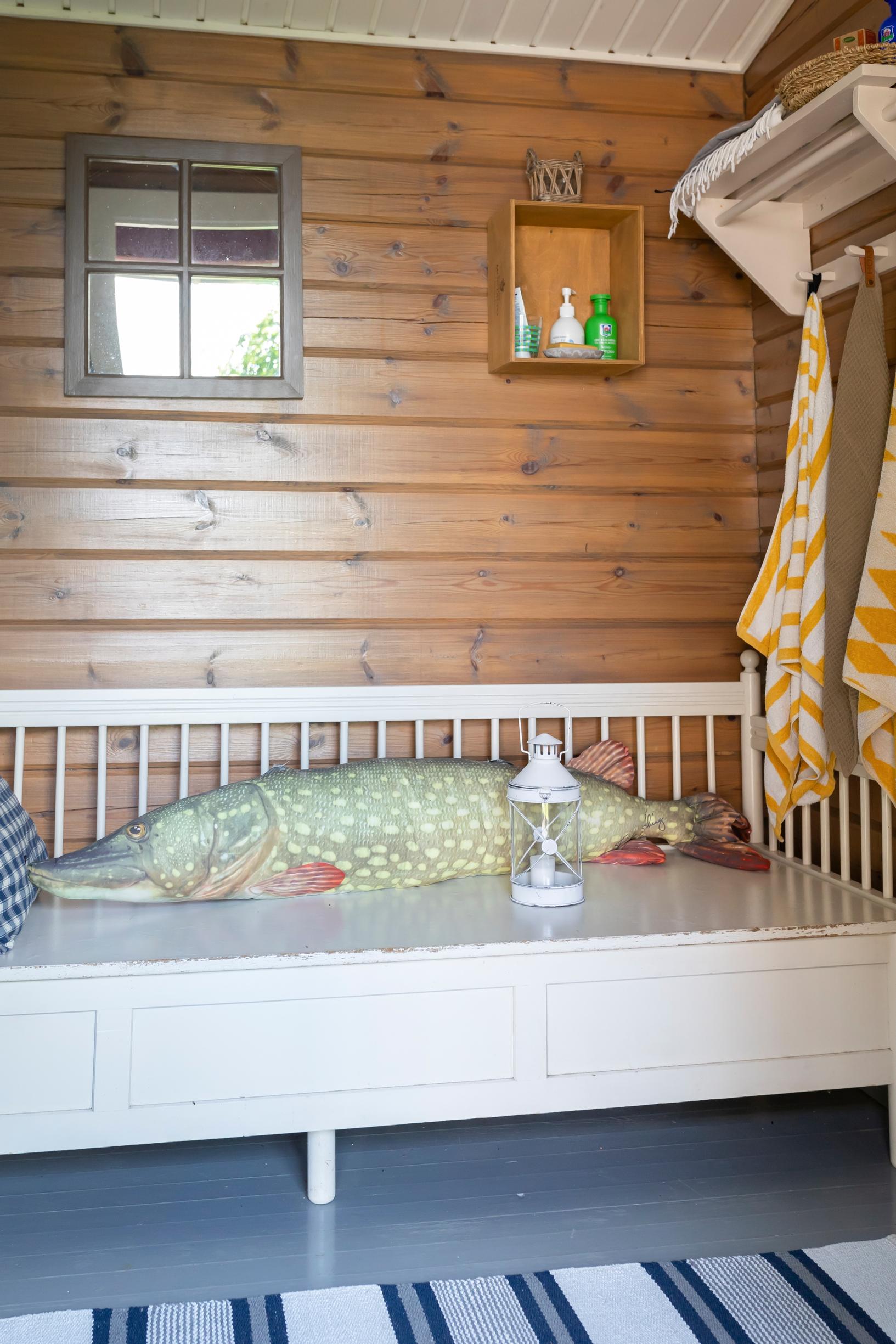 a pike-themed cushion on a wooden sofa, a coat rack, and a rug