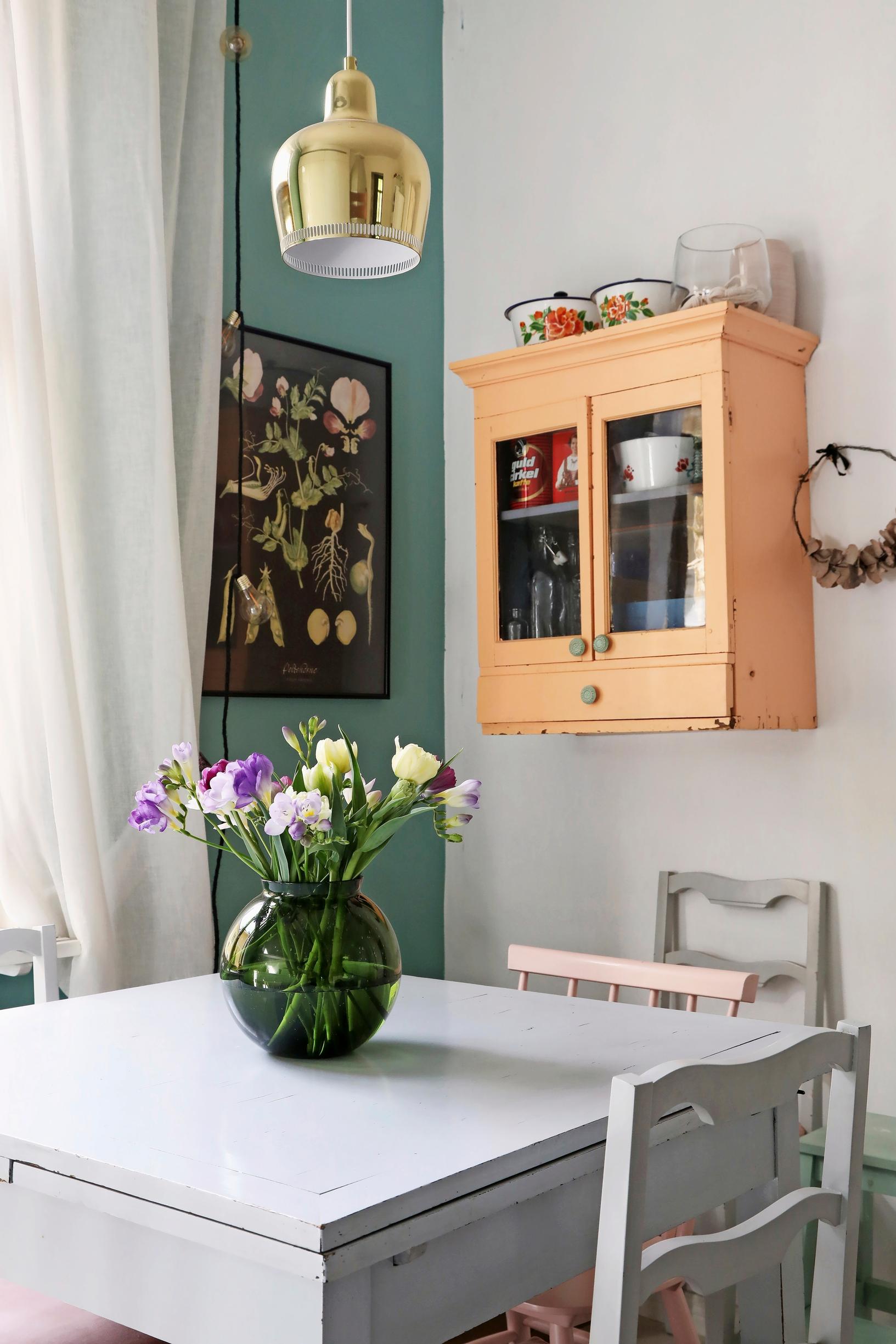 A photo of the kitchen in an old wooden home featuring a pink wall cabinet.