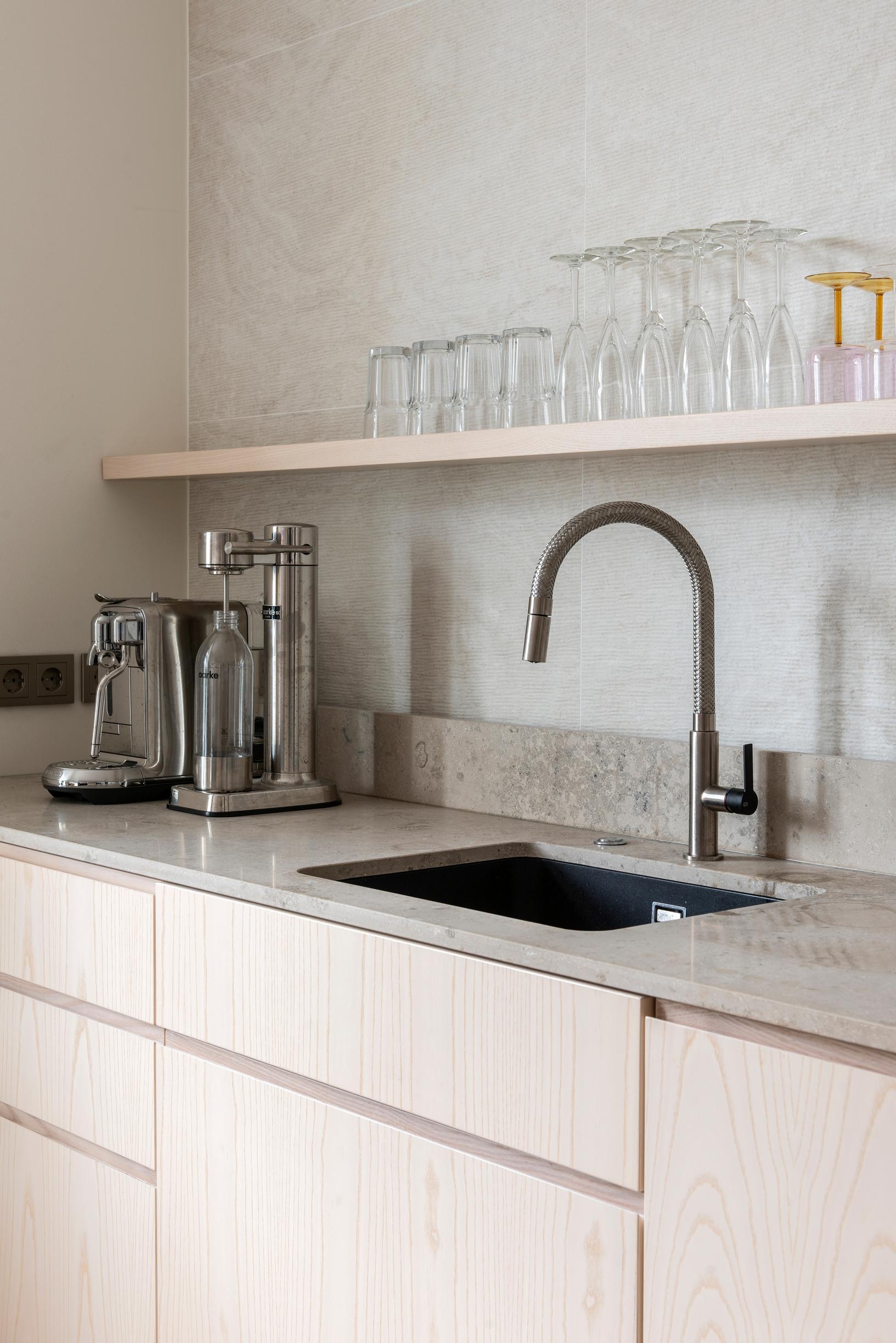 Limestone countertops and open shelving in a light-toned kitchen