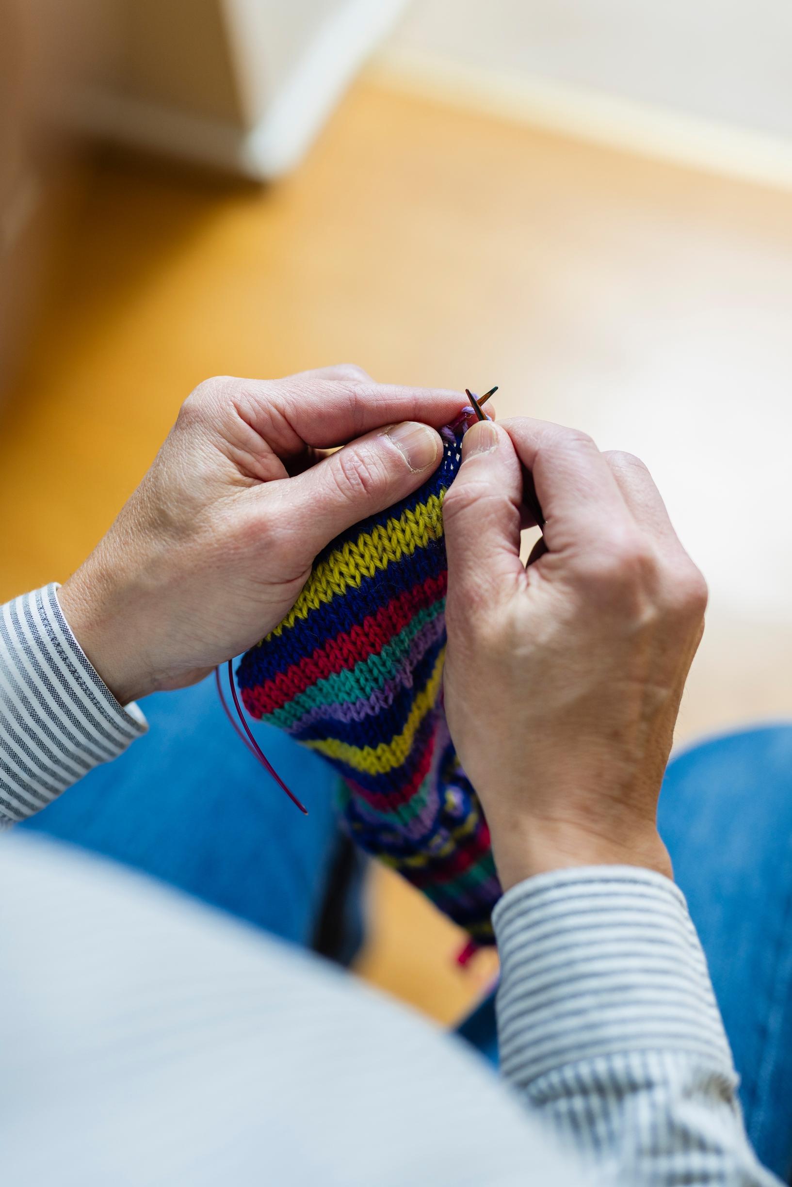man knitting a striped sock