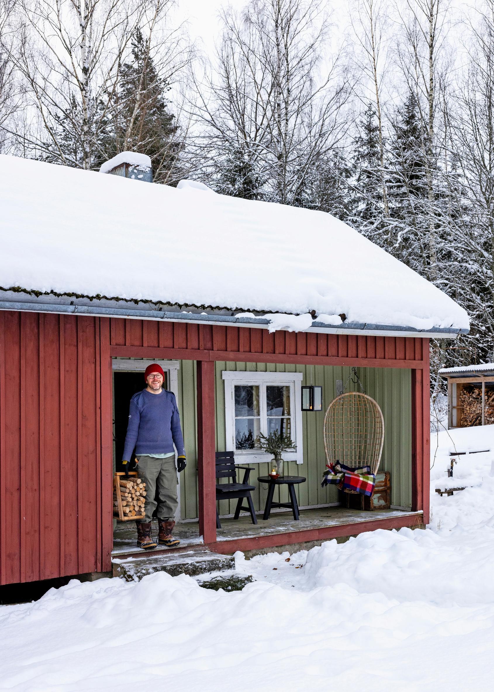 Klaus Aalto carrying logs at the garden sauna door, snow and a chair and table on the terrace