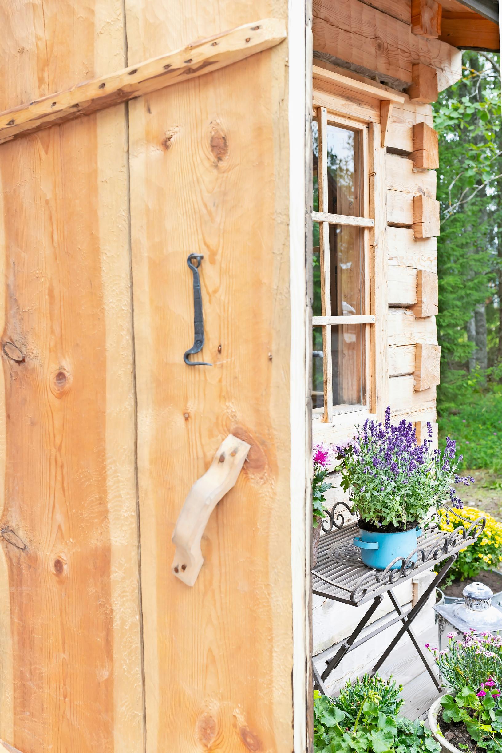 light-colored wooden door, flowers on the terrace, log building