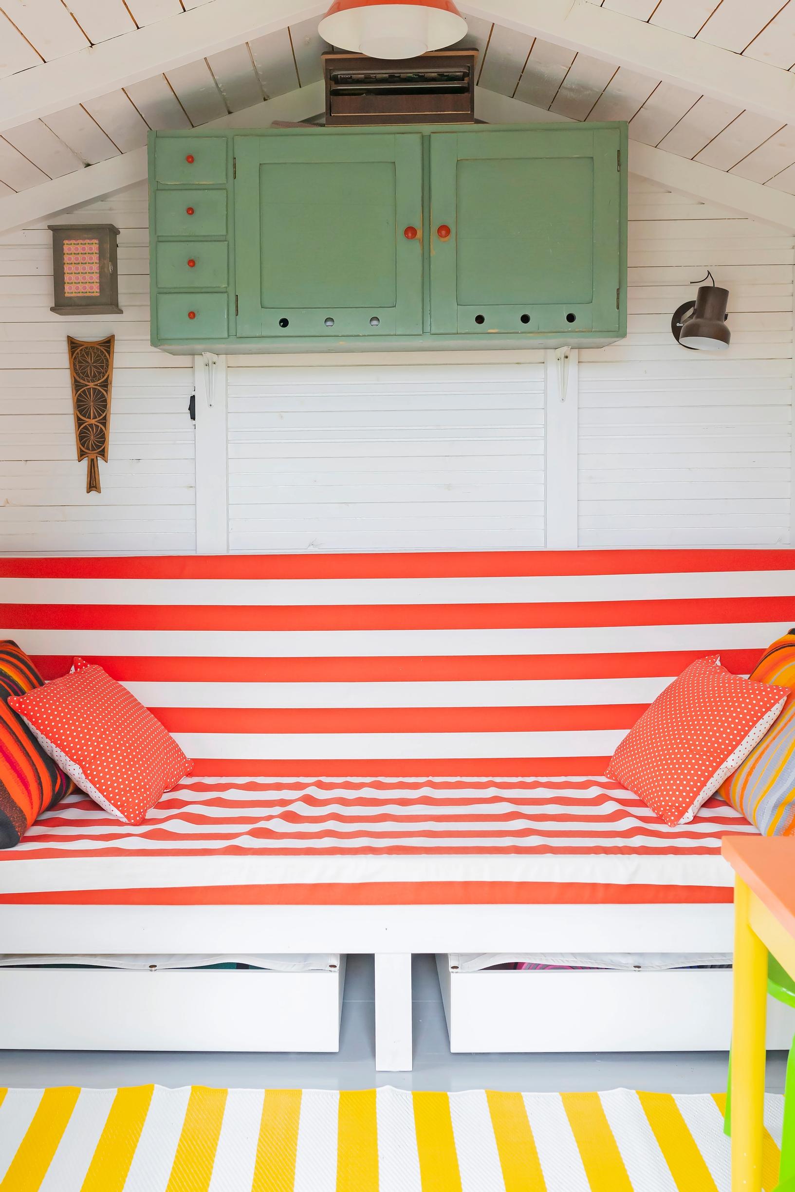a striped sofa and rug, a small green cabinet on the wall