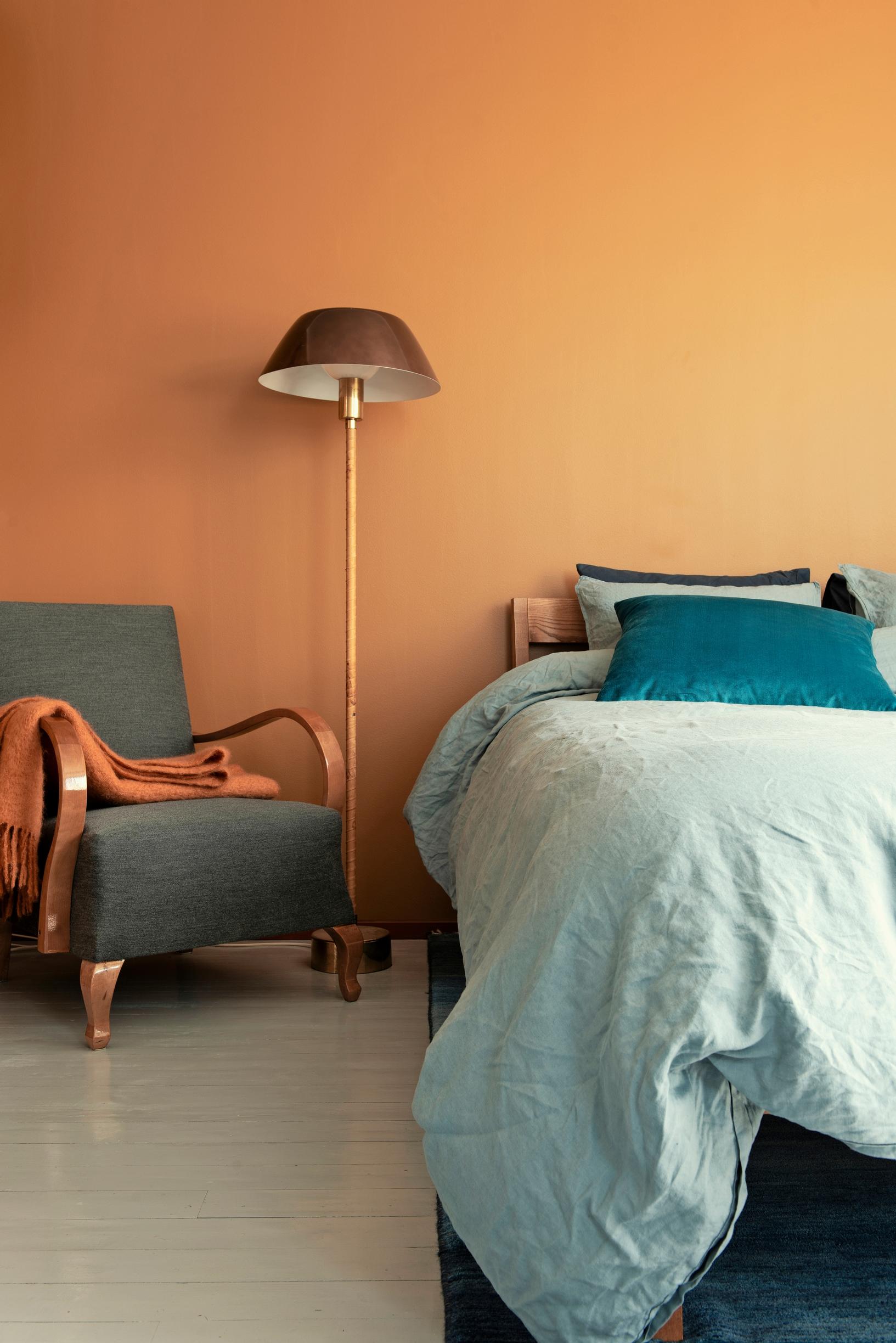 A bedroom featuring a chair built by his grandfather, a yellow wall, and colorful bedding.