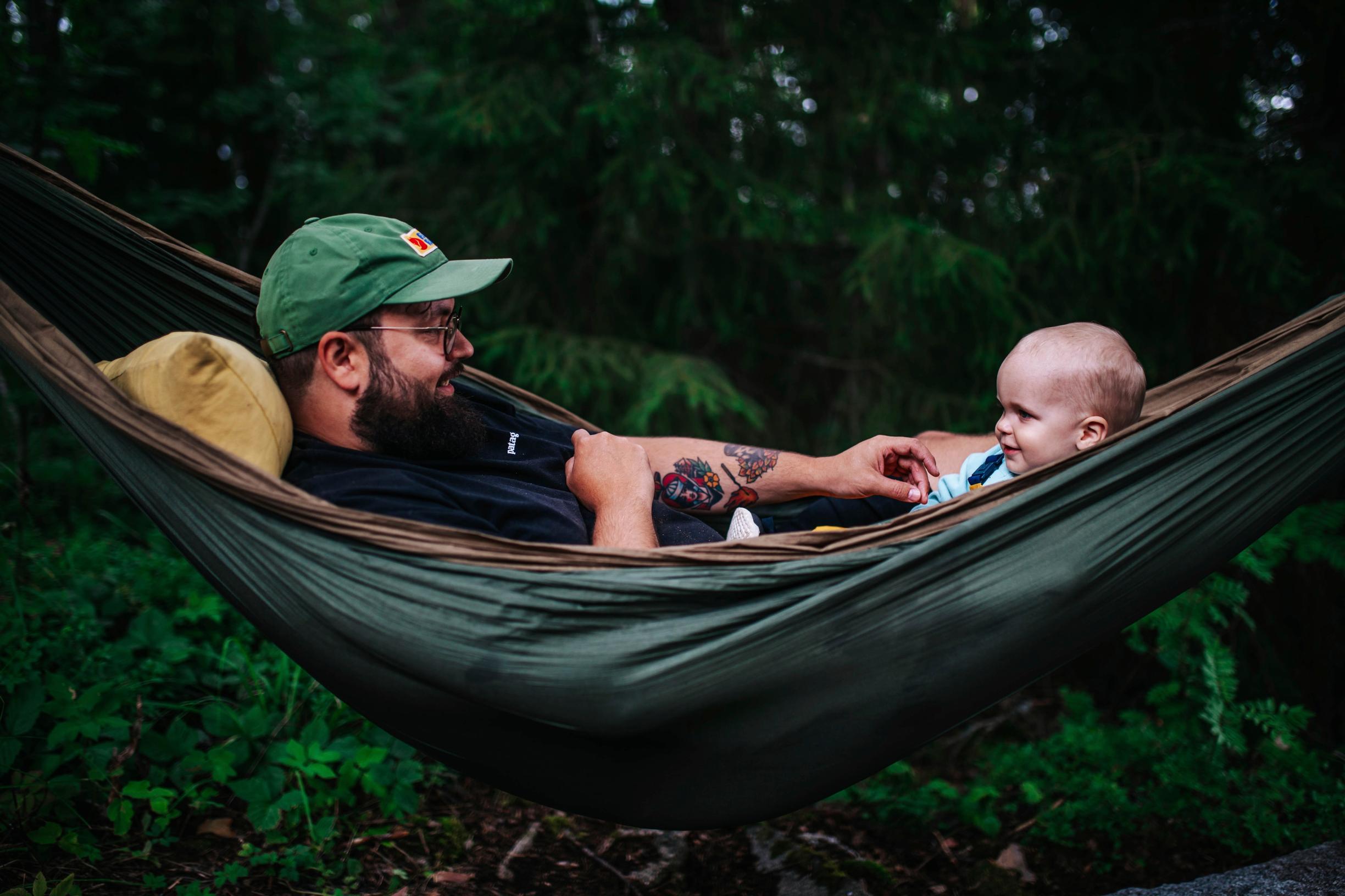 A father and toddler in a hammock.