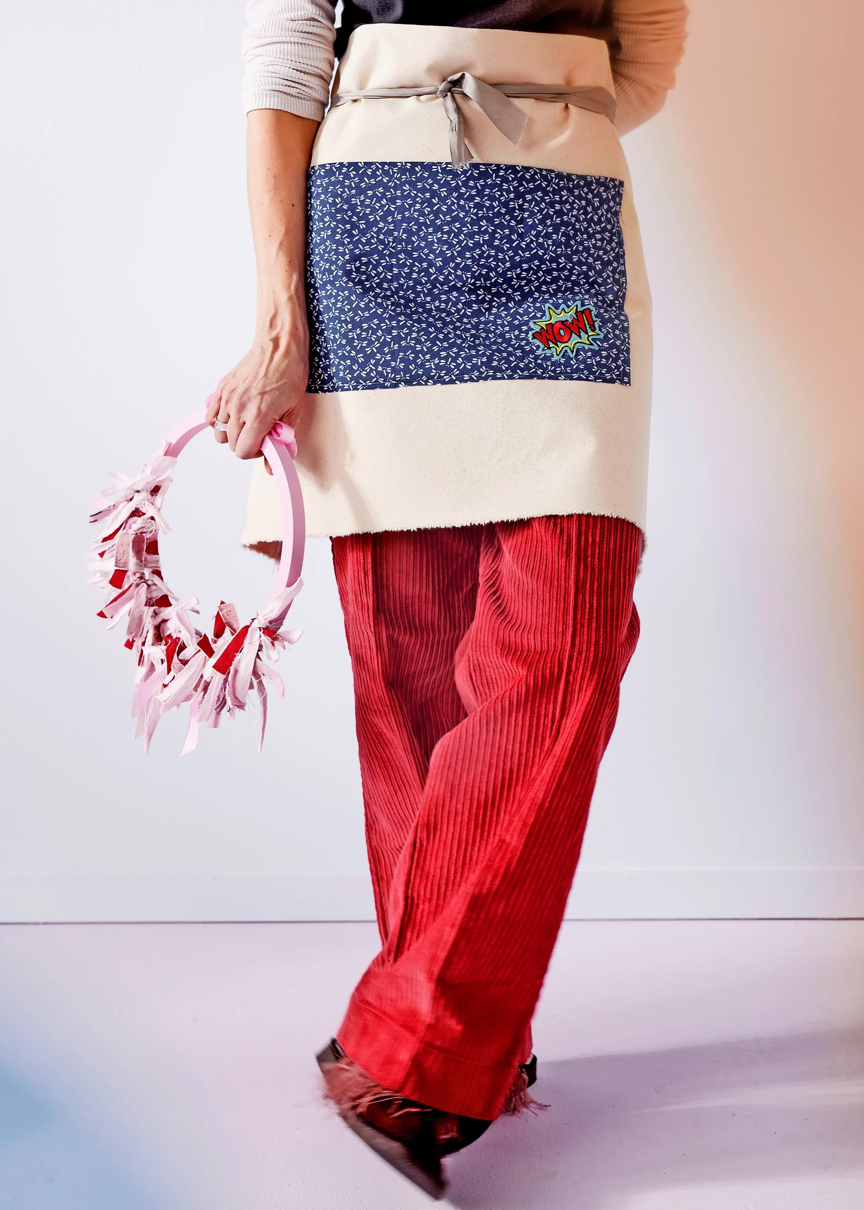 Model wearing a half-apron with an iron-on patch.