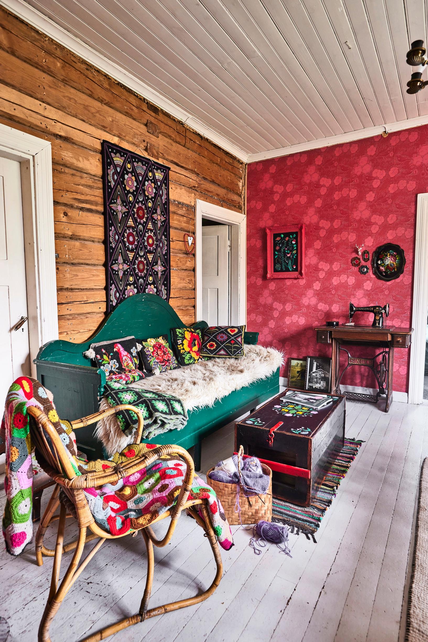 A green wooden sofa in front of a log wall