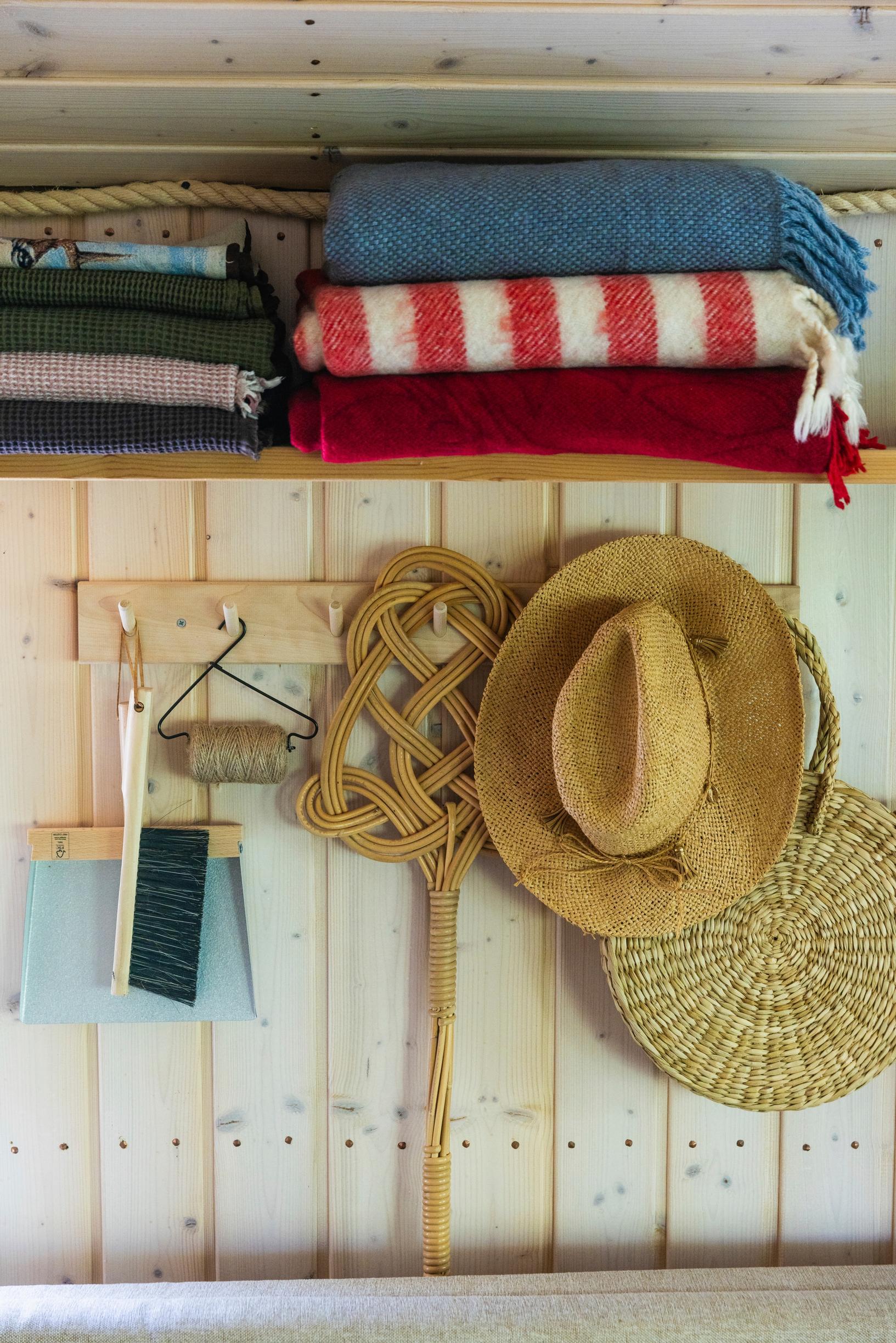 a carpet beater, hats, and a shelf on the wall