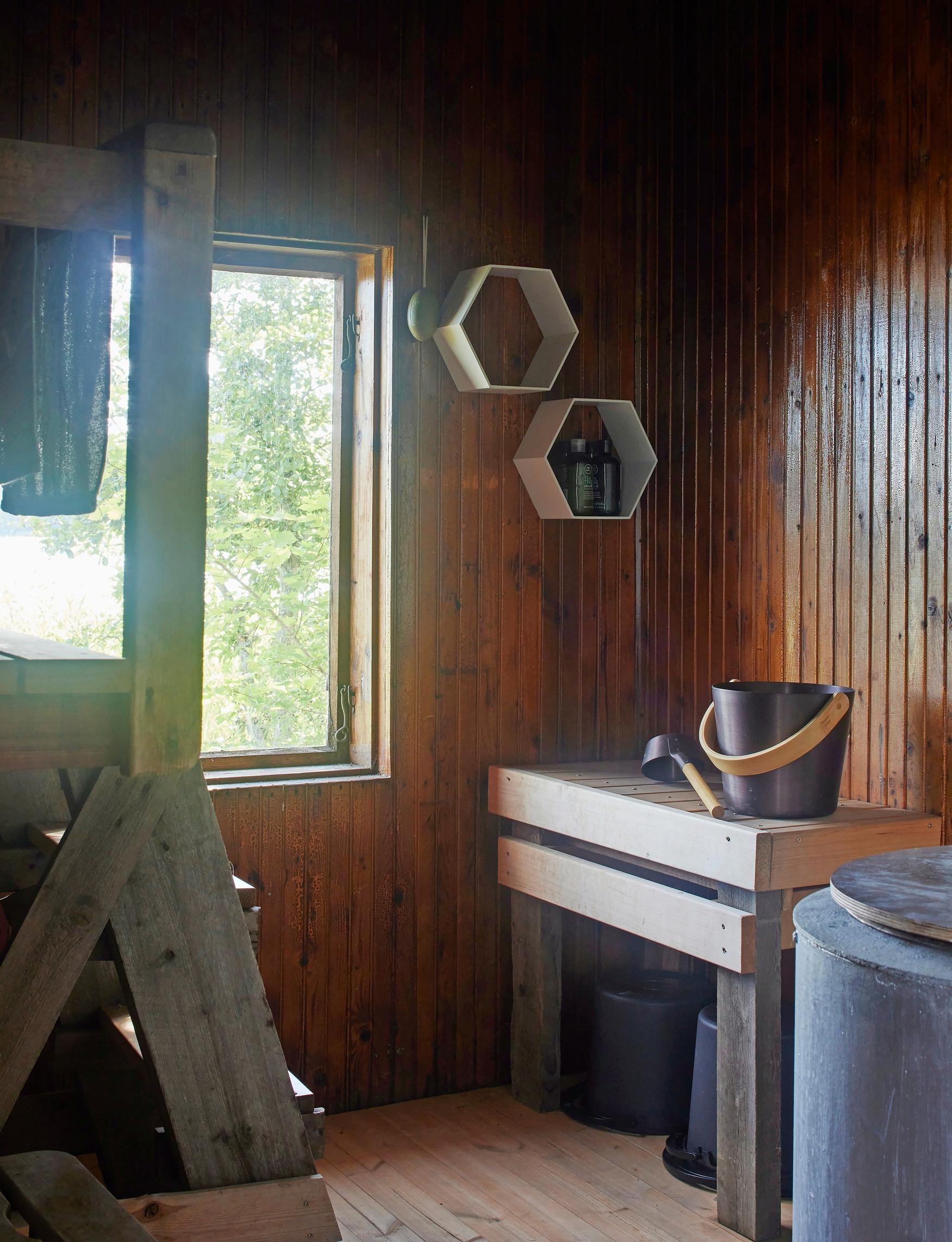 slat wall in the sauna, bucket and ladle on a bench, water tank, shelves on the wall