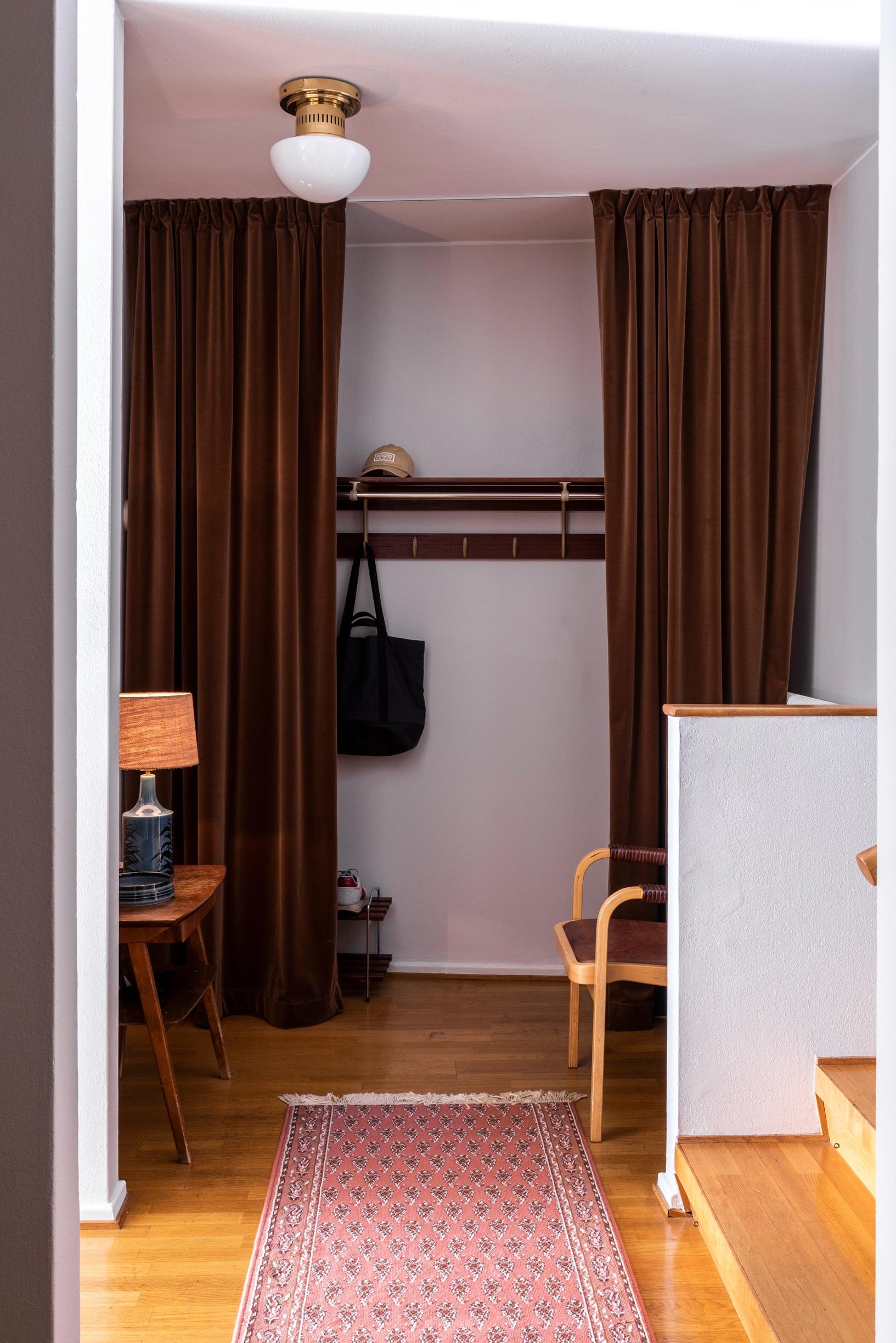 In the entryway: a coat rack and brown velvet curtains on both sides