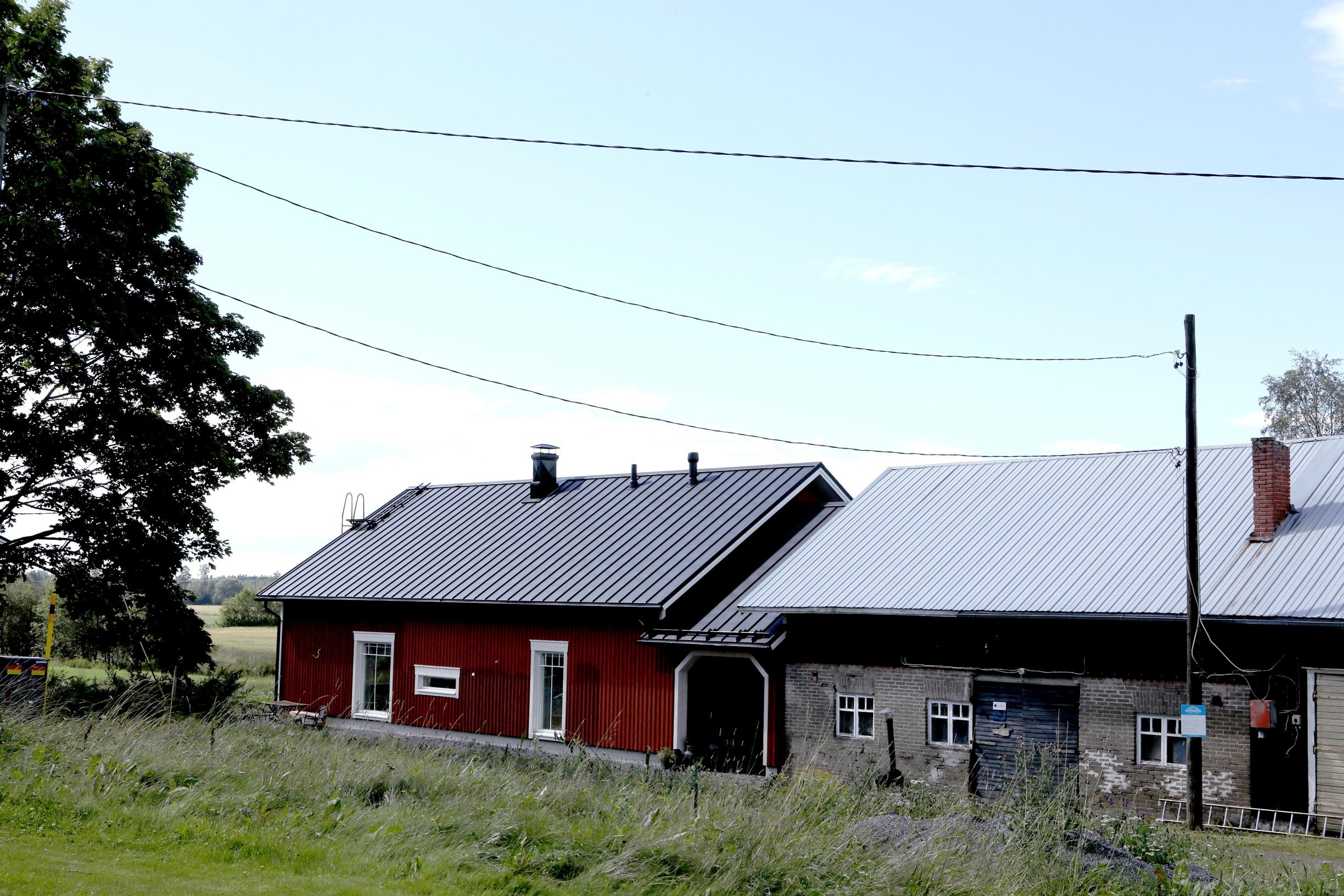 A red house connected to a gray barn by an archway.