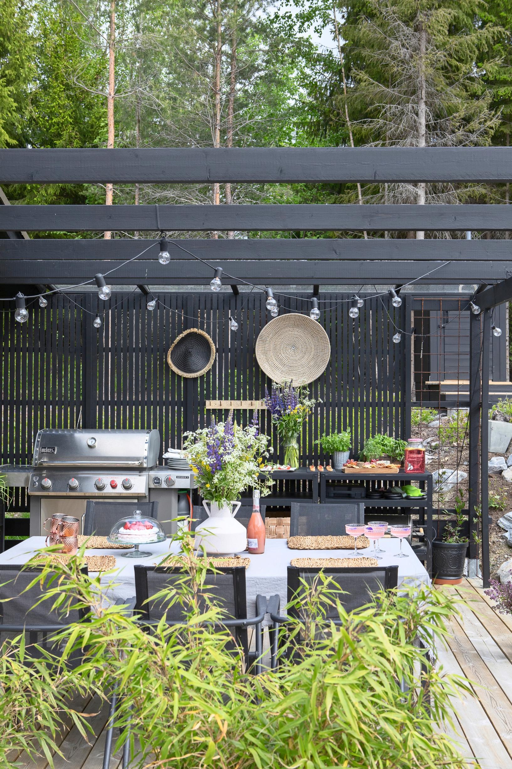 A slatted wall behind the black outdoor kitchen