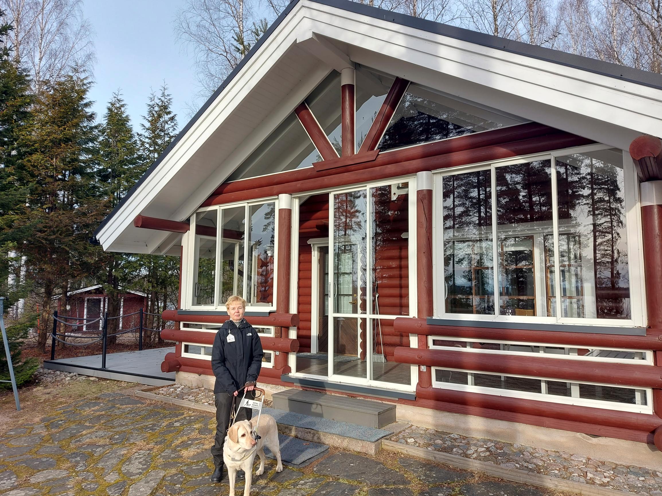 Merja Heikkonen with her guide dog, Esta, in front of the cabin
