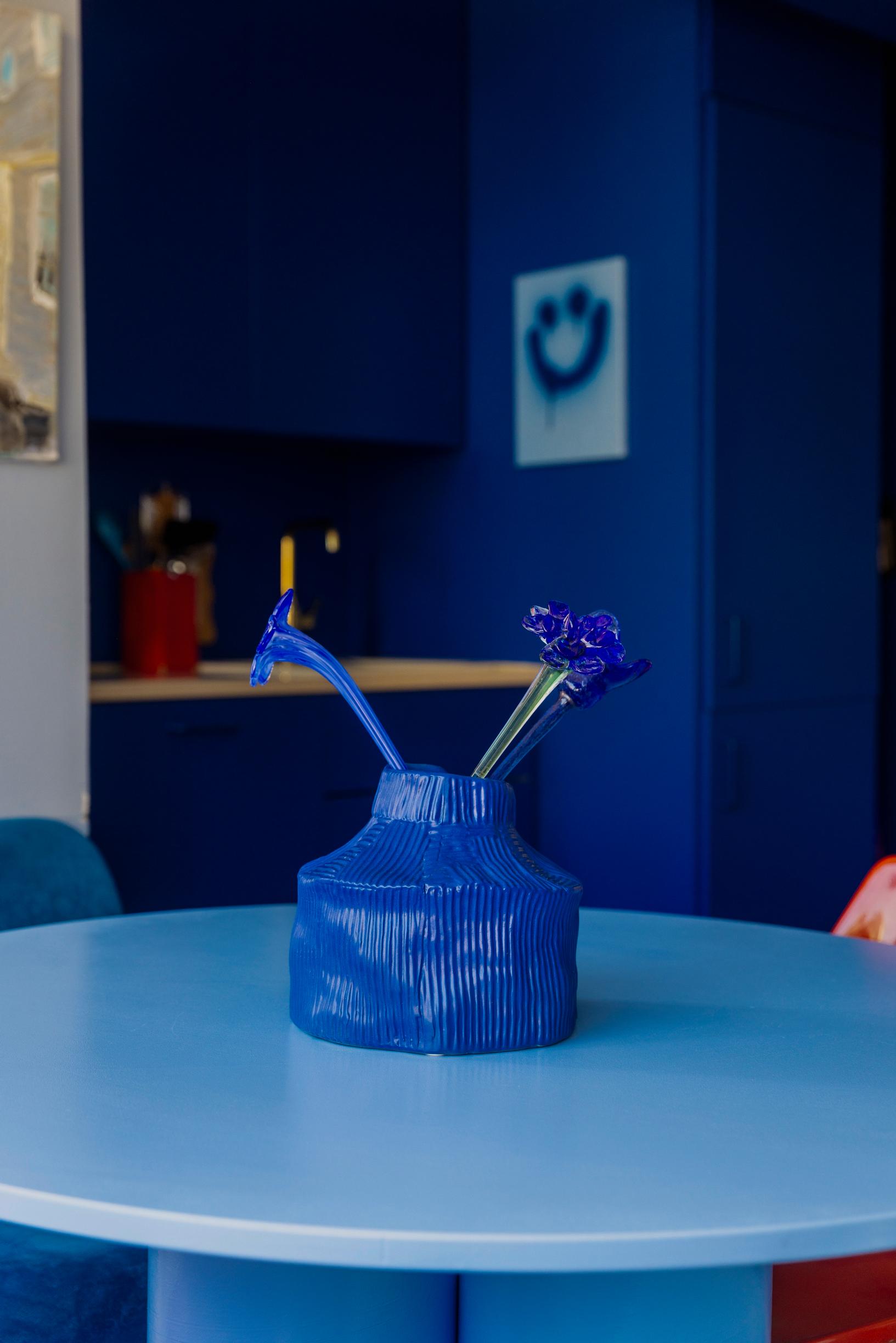 a blue vase and blue flowers on a blue table