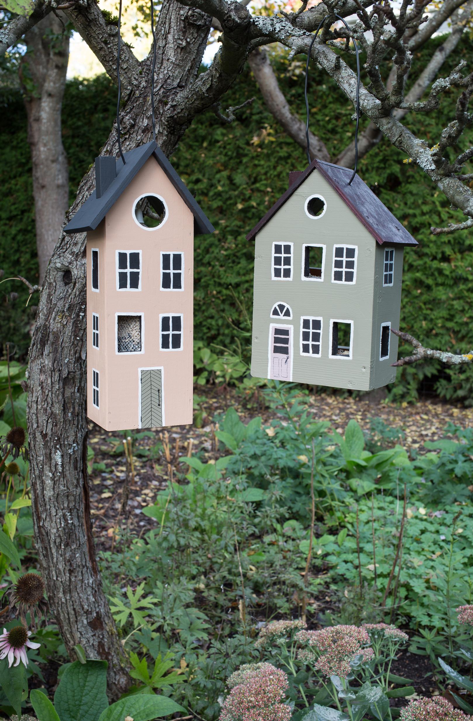 Bird feeder houses attached to a tree side by side