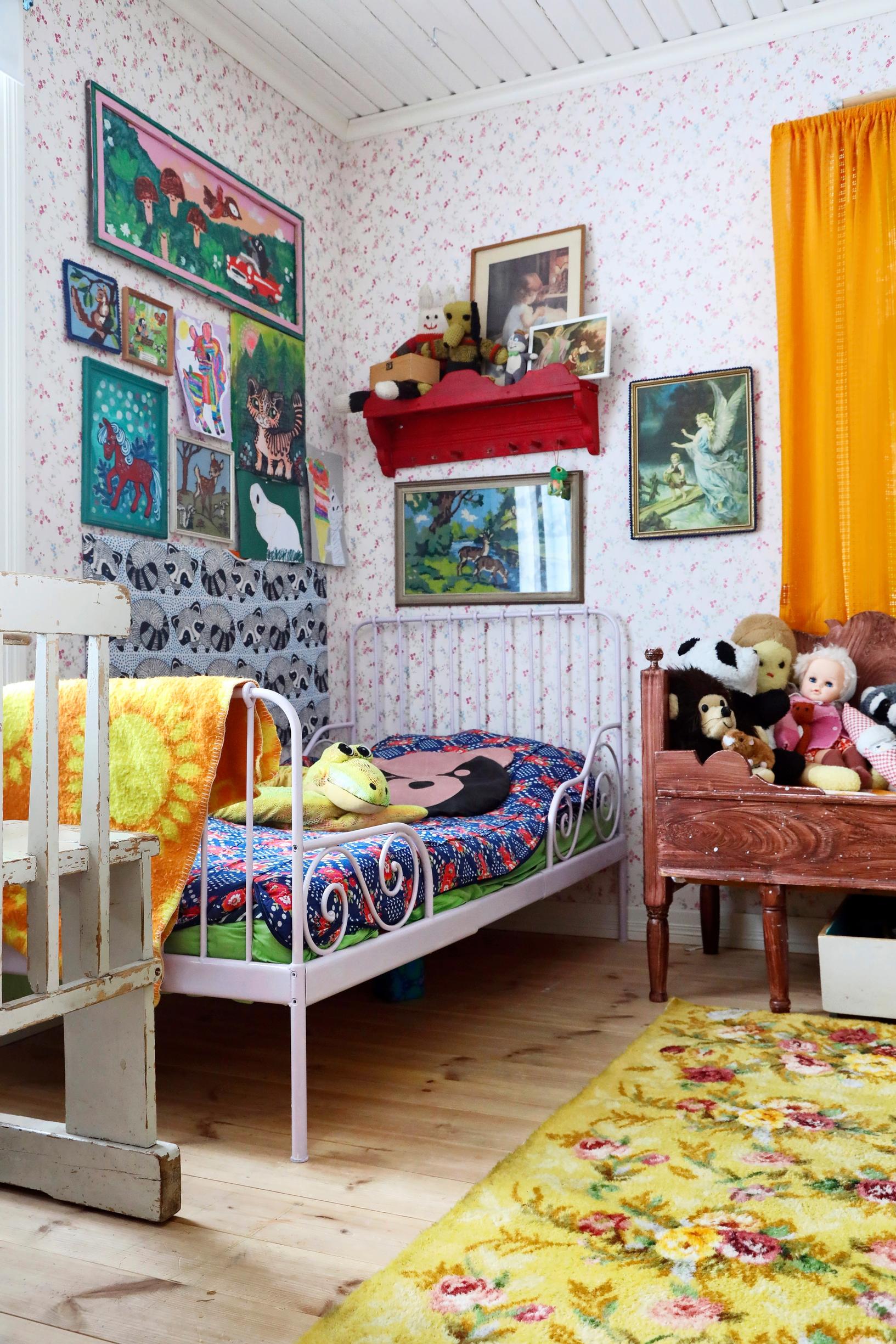Artwork and drawings above a metal-framed bed.