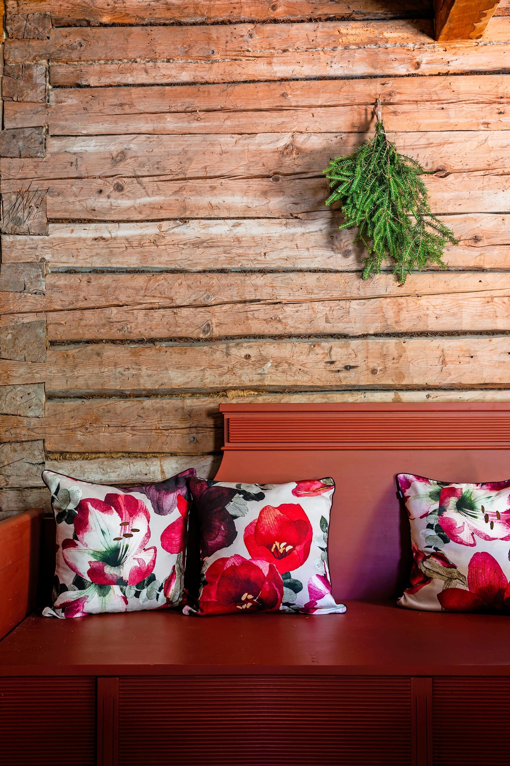 Floral throw pillows on a red wooden sofa.