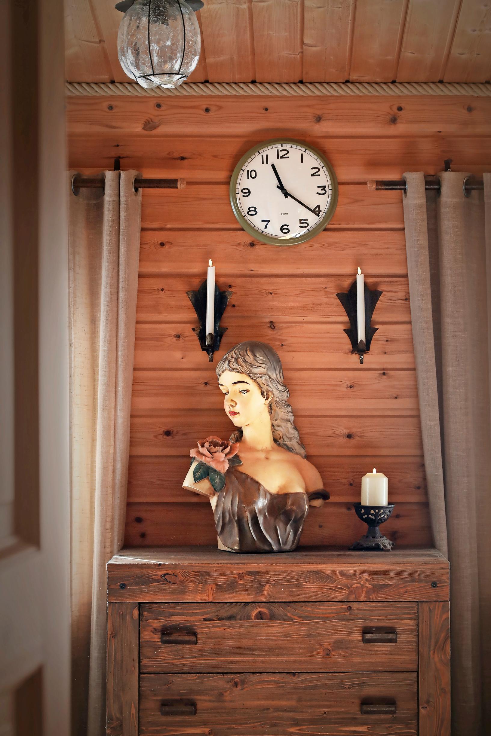A woman’s bust, a wooden dresser, and candelabras.
