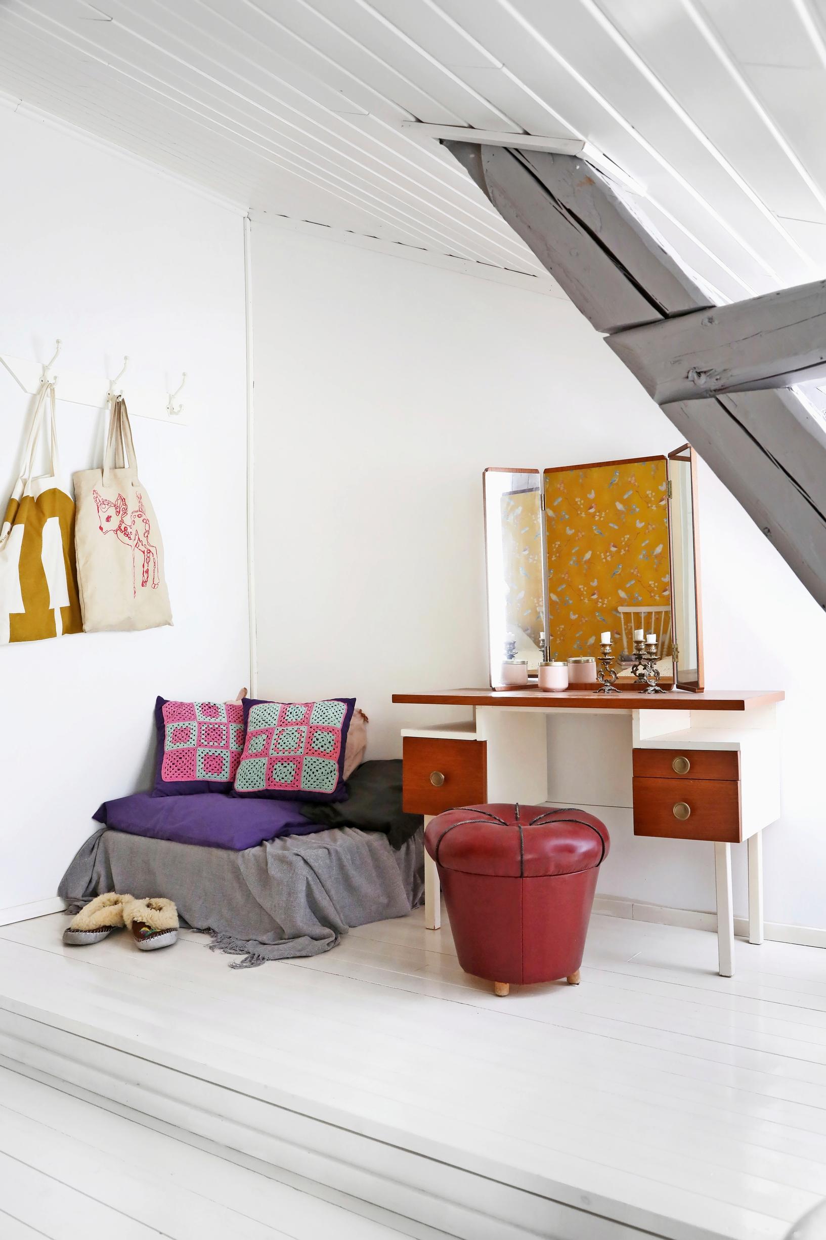 A photo of a bedroom corner with a cozy lounging spot and an old vanity table.